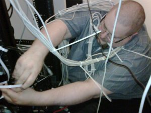 Computer systems administrator covered in network cables.